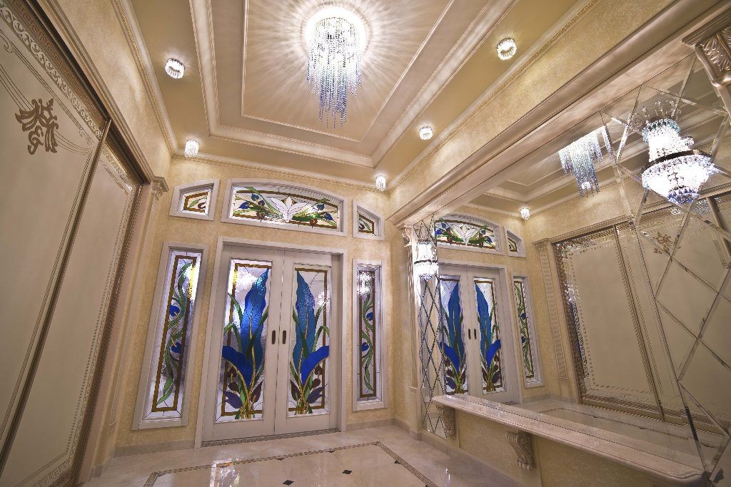 Luxurious room with stained glass doors, ornate decor, and sparkling chandeliers on the ceiling.